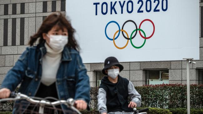 Cuclists in Tokyo ride past a Tokyo Olympics sign. Picture: Getty Images