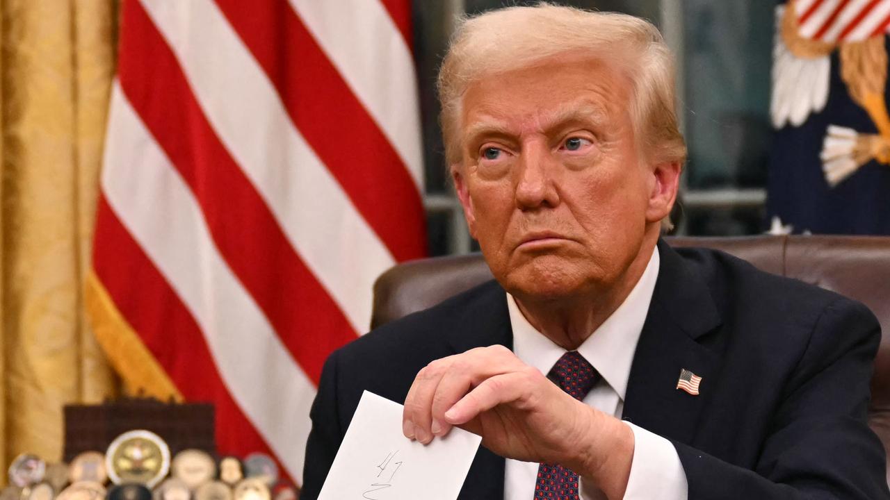 US President Donald Trump holds up outgoing President Joe Biden's letter as he signs executive orders in the Oval Office of the White House in Washington, DC, on January 20, 2025. (Photo by Jim WATSON / POOL / AFP)