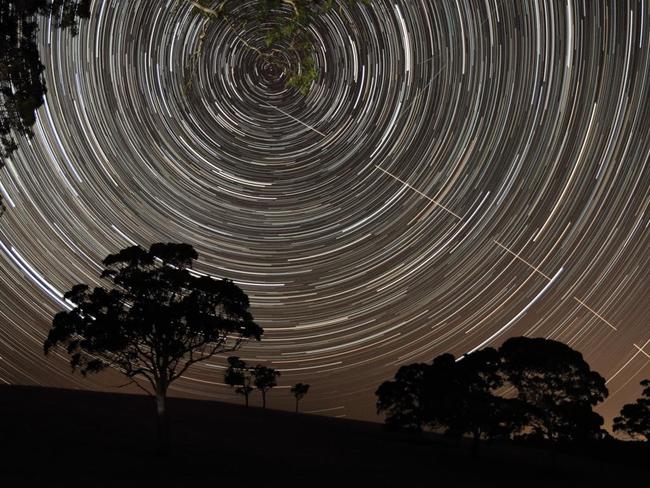Just Missed the Bullseye ... The International Space Station (ISS) appears to pierce a path across the radiant, concentric star trails seemingly spinning over the silhouettes of the trees in Harrogate, South Australia. Picture: Scott Carnie-Bronca, Insight Astronomy Photographer of the Year 2016 Young Competition Highly Commended