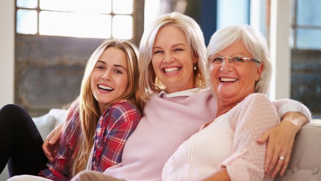 Grandmother With Mother And Adult Daughter Relaxing On Sofa, Smiling To Camera; happy seniors retirement generic family