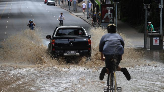 A car and a man riding his bike pass through the muddied streets of Brisbane’s CBD on Thursday, Jan. 13, 2011. Flood waters have slowly started to recede across Brisbane with the clean up effort.