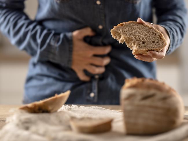 Woman can't eat bread and grain products because of gluten intolerance. A young celiac woman suffers from abdominal pain after eating fresh bread.
