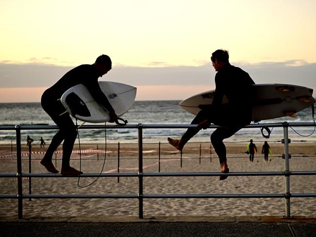 Surfers climb a fence ahead of Bondi Beach reopening to the public after five weeks. Picture: AAP