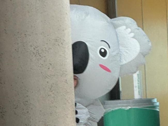 Janelle Spies, 33, of Noosa, hiding around the corner while waiting to welcome home her two unsuspecting sisters home from the USA, where they now live. Chelsea Bartlett, 29, and Katie Bartlett, 37, flew into the Brisbane domestic airport on the same day as they family gathered for a family wedding. Picture: Supplied