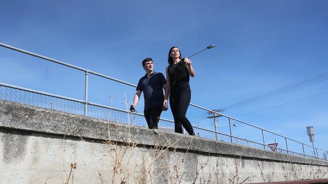 St Albi‘s Bar and Eatery owner, Lucy Baker, right, with Northern Suburbs Rail Action Group President Ben Johnston at the rail crossing on Albert Road, Moonah. Picture: LUKE BOWDEN