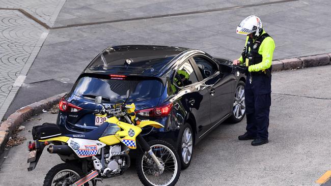 Generic picture of a police office issuing an infringement notice to a driver during peak-hour in Brisbane.