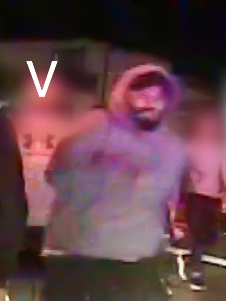 Person V is described as being a man of Mediterranean/Middle Eastern appearance, solid build, with a dark coloured beard. He is shown wearing a grey hooded jumper, black cap, black shorts and white shoes. Picture: Supplied / NSW Police