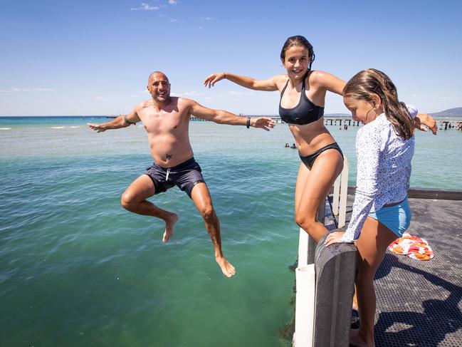 John Rousakis takes the plunge on New Year’s Eve 2021 at Rye with daughters Amelia, 13, and Stephanie, 8. Picture: Mark Stewart