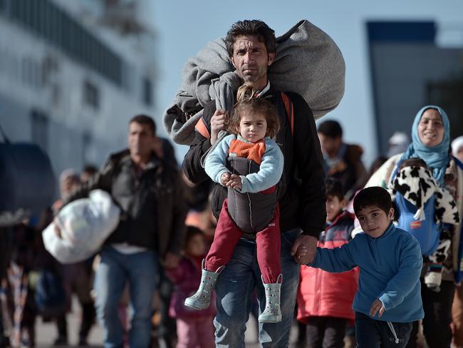 (FILES) This file photo taken on February 1, 2016 shows thousands of migrants and refugees walking through the port of Piraeus after arriving from the Greek islands of Lesbos and Chios. A year ago, the tragic death of a three-year-old Syrian boy shocked Europe as an unprecedented crisis saw hundreds of thousands of migrants and refugees arrive on the continent. The IOM says 1,046,599 migrants and refugees reach Europe in 2015, with a monthly peak of more than 221,000 in October that year. More than 821,000 travel through Greece, with the vast majority making the perilous journey across the Aegean Sea in rickety, overcrowed boats from Turkey's shores.  / AFP PHOTO / LOUISA GOULIAMAKI