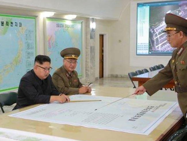 North Korean leader Kim Jong-un is presented with plans to launch ballistic missiles towards the US territory of Guam. The map in front of him details the flight path of a missile from North Korea towards the strategically significant Pacific island. Picture: KCNA