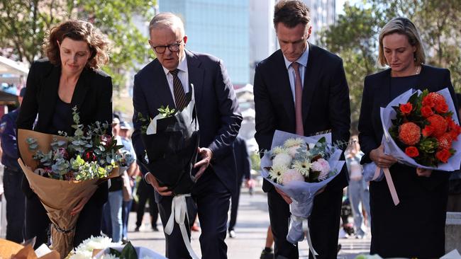 Wentworth MP Allegra Spender, Prime Minister Anthony Albanese and New South Wales Premier Chris Minns leave flowers outside the Westfield Bondi Junction shopping mall in Sydney on Sunday. Picture: David Gray/AFP