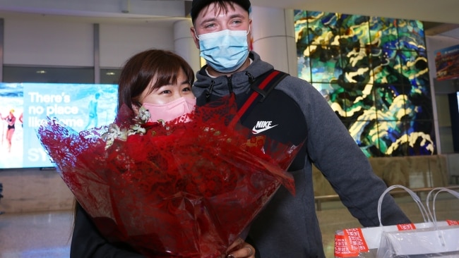 A couple are reunited as early morning flights arrived from Los Angeles, Japan and Singapore. Picture: Getty Images