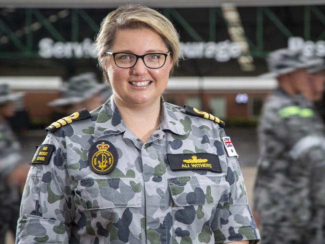HMAS Cerberus Recruit School Commanding Officer, Commander Alisha Withers, RAN, standing within the Recruit School grounds as recruits march past conducting drill training.