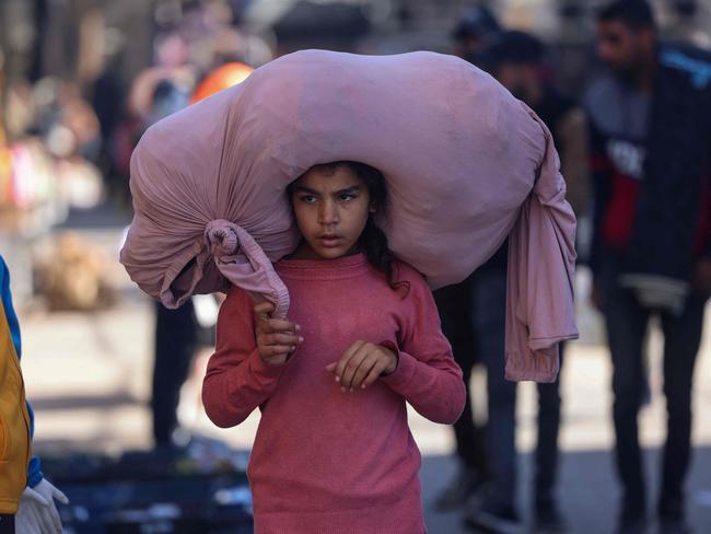 A Palestinian girl walks while carrying a bundle on her head on a busy street in Rafah. Picture: AFP