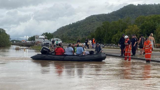 Cairns flood 2023: Royal Australian Navy personnel work with civilian emergency services to evacuate members of the public from Holloways Beach using a stretch of the Captain Cook Highway near the Barron River Bridge. Picture: Supplied