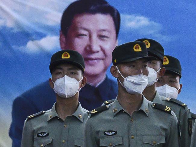 Soldiers of the People's Liberation Army's Honour Guard Battalion wear protective masks as they stand at attention in front of photo of China's president Xi Jinping. Picture: Kevin Frayer