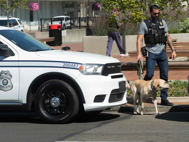 A Dayton police officer and his dog return to their vehicle after sweeping the Springfield City Hall grounds for explosives. Picture: AFP