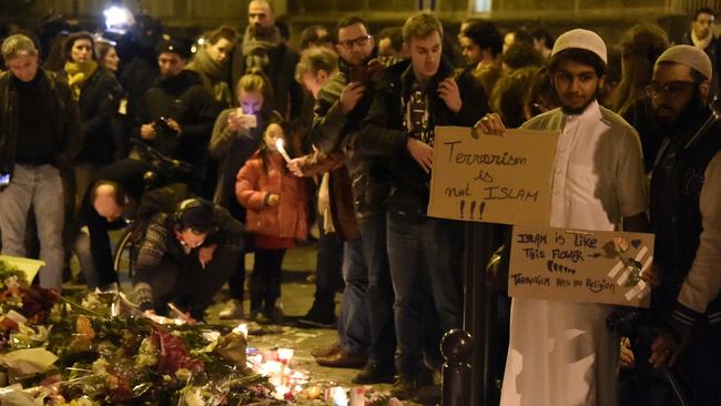 A Muslim holds a placard reading ‘Terrorism is not Islam. Islam is like this flower. Terrorism has no religion’ during a gathering at Le Carillon restaurant, one of the site of the attacks in Paris. Picture: Dominique Faget