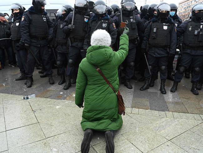 TOPSHOT - A woman holding an icon kneels in front of a group of riot police during a rally in support of jailed opposition leader Alexei Navalny in downtown Moscow on January 23, 2021. - Navalny, 44, was detained last Sunday upon returning to Moscow after five months in Germany recovering from a near-fatal poisoning with a nerve agent and later jailed for 30 days while awaiting trial for violating a suspended sentence he was handed in 2014. (Photo by Kirill KUDRYAVTSEV / AFP)