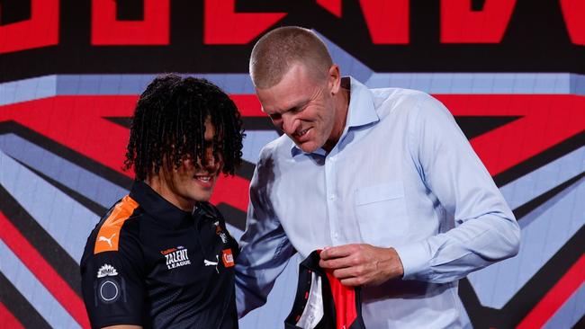 MELBOURNE, AUSTRALIA - NOVEMBER 20:  The number 13 pick, Isaac Kako is presented his Essendon  jumper by Dustin Fletcher during the 2024 Telstra AFL Draft at Marvel Stadium on November 20, 2024 in Melbourne, Australia. (Photo by Michael Willson/AFL Photos via Getty Images)