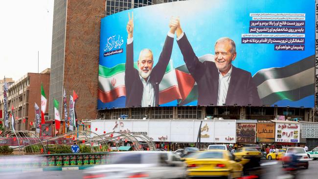 Vehicles drive past a huge billboard depicting Iranian President Masoud Pezeshkian (R) and slain Palestinian Hamas leader Ismail Haniyeh at Tehran's Valiasr Square. Picture: AFP.