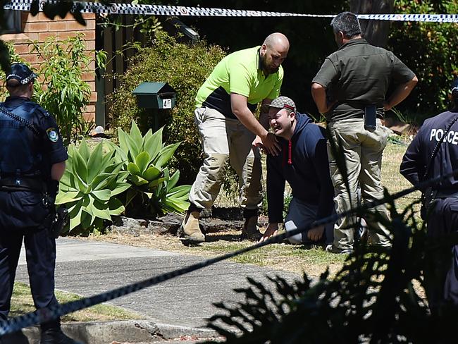 A visibly distraught man is held back by friends and police at the scene. Picture: AAP