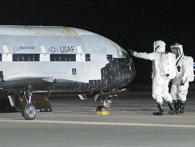 Pet project ... US Air Force personnel examine an X-37B after it returned from its space deployment.