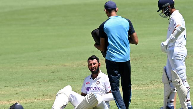 Battered, but not beaten: Cheteshwar Pujara takes a moment after one of the many blows he took. Picture: Getty