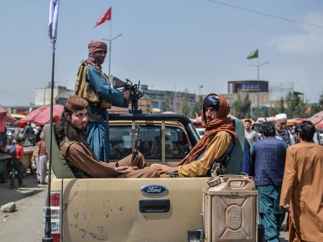 TOPSHOT - Taliban fighters on a pick-up truck move around a market area, flocked with local Afghan people at the Kote Sangi area of Kabul on August 17, 2021, after Taliban seized control of the capital following the collapse of the Afghan government. (Photo by Hoshang Hashimi / AFP)