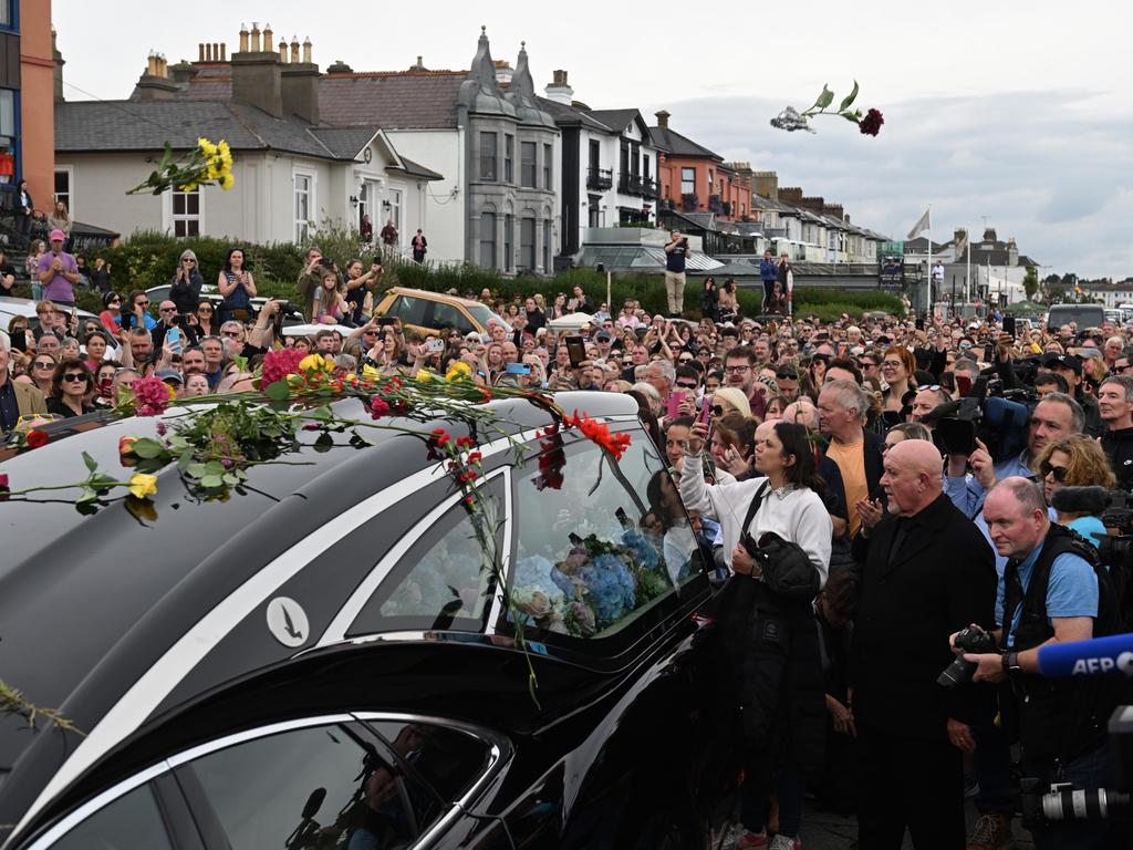 Crowds throw flowers as they swarmed the hearse carrying O'Connor's coffin. Picture: Getty Images