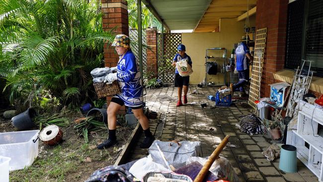 Jake Westmore, 10, and Maliq Wray, 10, of the Brothers Leagues Club help clean up a property that was flooded in Mimosa Street, Holloways Beach. Picture: Brendan Radke