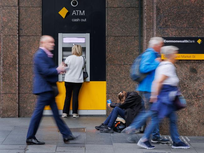 Shoppers on mobile phones walk past the Commonwealth Bank Branch in Sydney. Picture: NCA NewsWire