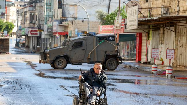 A Palestinian man in a wheelchair near an Israeli army vehicle, following an overnight army raid in Jenin in the occupied West Bank. Picture: Jaafar Ashtiyeh