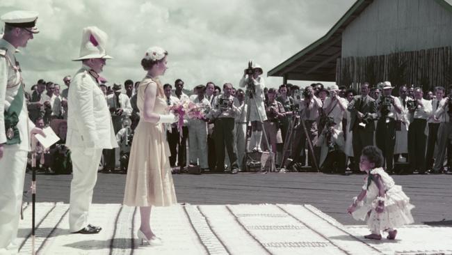 The Queen smiles down at Mei Kainona, as the four year old Fijian girl bows gravely before presenting her with a bouquet of native flowers in Suva in 1953. Picture: Getty