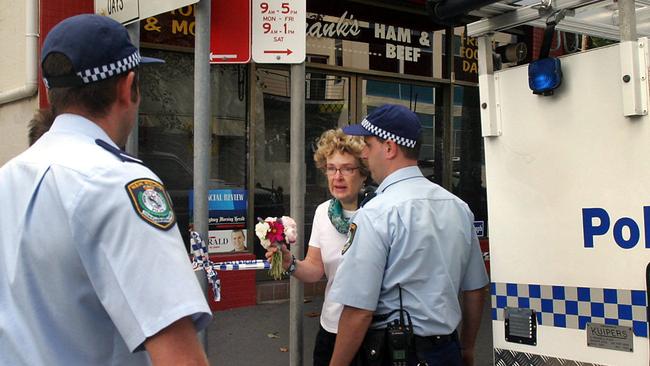 A distraught woman arrives with a bouquet of flowers to the scene of the murder of store owner Frank Newbery, 87, in Union St, Newcastle.