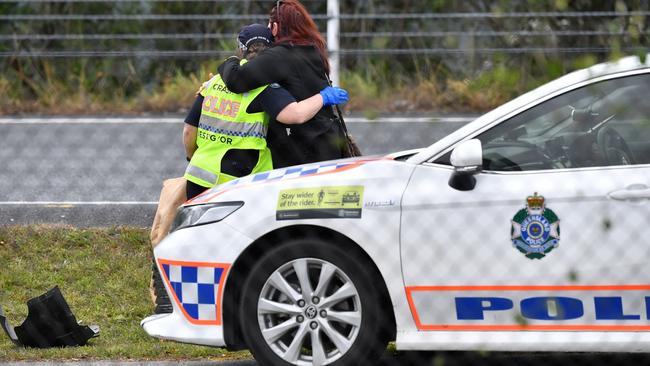 Queensland Police Officers are seen comforting each other at the scene where 53-year-old Senior Constable David Masters was killed on the Bruce Highway at Burpengary. Picture: AAP Image/Darren England