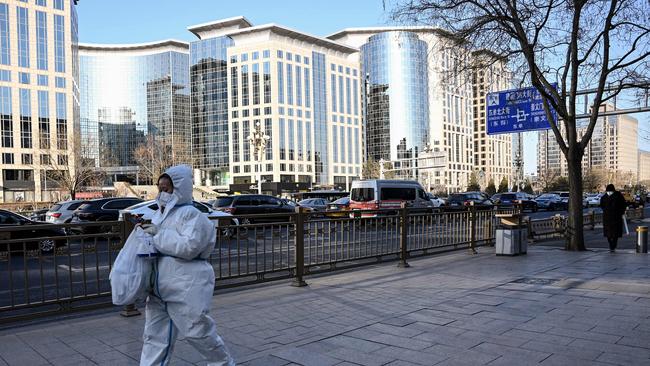 A woman wearing protective equipment walks along a street in Beijing on Boxing Day.