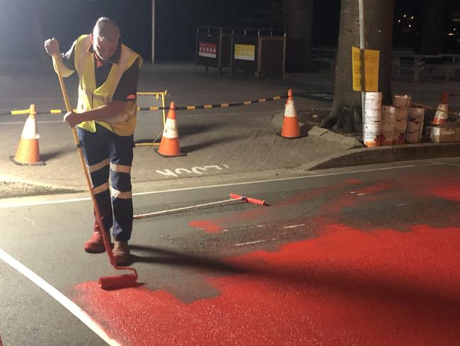 A ontractor painting the road surface at the intersection of Wentworth St and South Steyne at Manly on Sunday night ahead of installing a '3D' pedestrian crossing as part of a trial of new crossings conducted by Northern Beaches Council and Transport for NSW. Picture: Jim O'Rourke