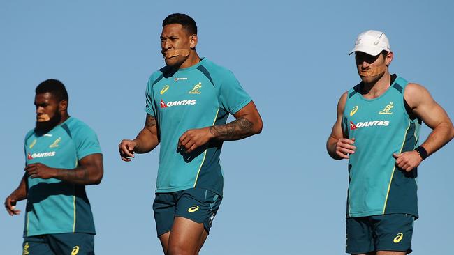 Wallabies players (l-r) Marika Koroibete, Israel Folau and Bernard Foley with their mouths taped shut as they run a hill session at Sydney Park on Saturday.