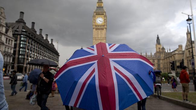 Pedestrians shelter from the rain near the Big Ben clock face and the Elizabeth Tower at the Houses of Parliament in central London. Picture: AFP