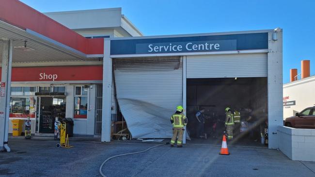 A woman was injured after she crashed through a garage door and collided with a car at a Yamba service station. Photo: Yamba Fire Rescue 510.