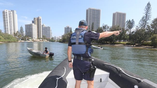 Water police sergeant Tony Nelson directs teenagers towards shore at Macintosh Island. Picture: Mike Batterham.