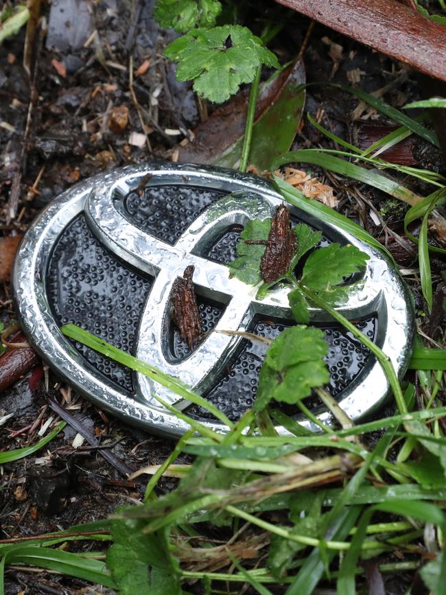 A badge from the Toyota vehicle crushed by a tree is part of the wreckage remaining near the scene of the accident. Picture: David Crosling