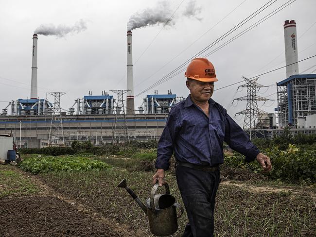 A worker waters plants in front of a coal fired power plant on October 13 in Hanchuan, Hubei province, China. Picture: Getty Images