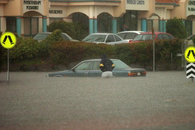 Gold Coast, June 30, 2005. A man inspects a submerged vehicle at a flooded intersection at Varsity Lakes on Queensland’s Gold Coast today. Widespread flooding has hit the popular tourist area, known for its sunshine and sandy beaches, with reports of rainfall reaching 80mm per hour in some regions. (AAP Image/Tony Phillips)
