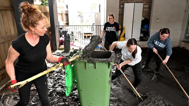 TOPSHOT - People clear mud from a property damaged by floods in the Melbourne suburb of Maribyrnong on October 15, 2022. - Australia reported the first fatality from days of widespread flash flooding on October 15, 2022 despite heavy rains easing and flood levels topping out across much of the southeast. Hundreds of homeowners began a long clean-up after storm waters engulfed streets, houses and cars across three states, with Melbourne suburbs among the worst hit. (Photo by William WEST / AFP)