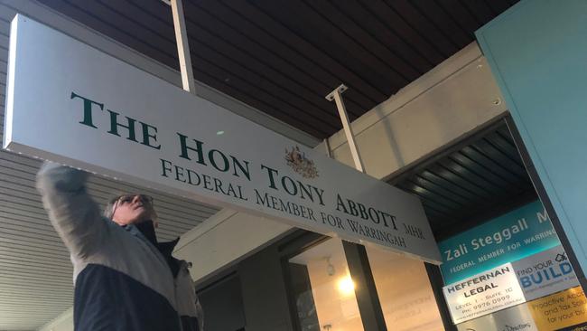 Grant Wiles, from Absolute Sign Solutions at Brookvale, works to replace the Tony Abbott signs outside the Warringah electorate office.