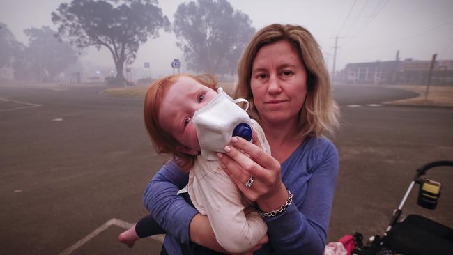 Mum Laura Langmead tries to put a breathing mask over her daughter Evie 1, to help filter the smoke in Mallacoota. Picture: David Caird