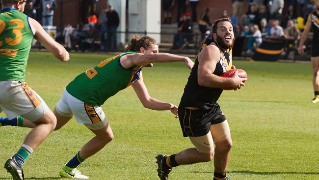 Golden Grove's Connor Dodd tries to tackle Brighton's John McPherson during last season’s division three grand final. Both clubs have been promoted to the second tier this season. Picture: AAP Image/Matt Loxton.