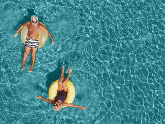 High angle view photo of a senior couple floating in the ocean while using swimming and floating devices; Retirement, travel generic retirees